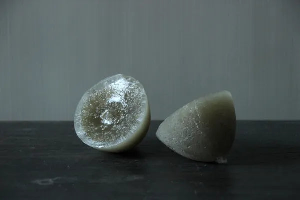 Twee olijfgroene grijze drijfkaarsen met gladde waxlaag