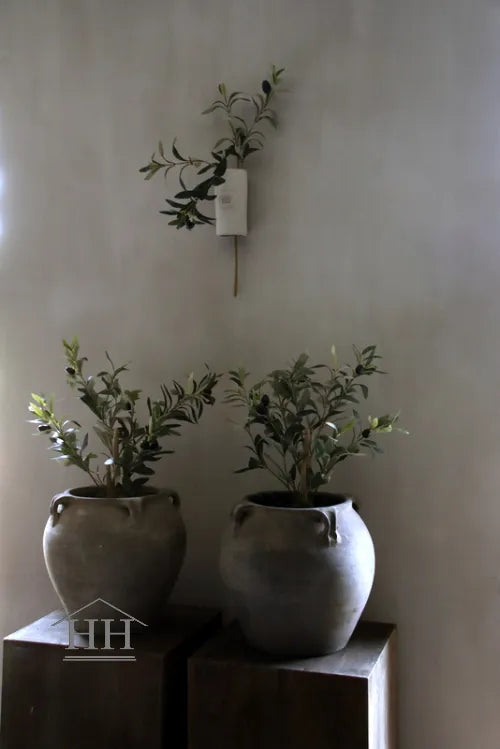 Betonnen wandvaas met kunsttak aan de muur