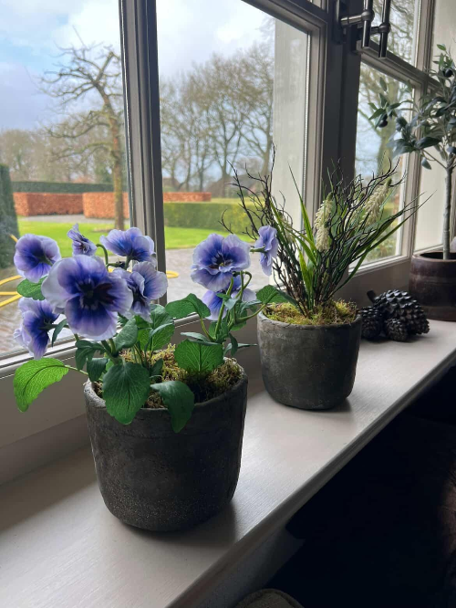 Kunstviooltjes in pot op de vensterbank