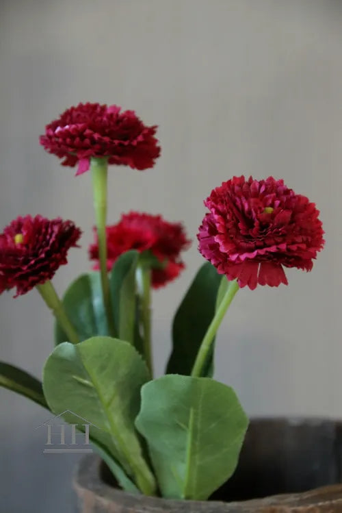 Kunstbloemen van donkerroze madeliefjes met groene bladeren