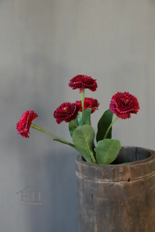 Bos zijdeachtige madeliefjes in donkerroze kleur met blad, geplaatst in houten vaas